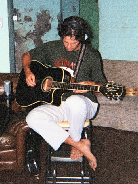 A picture of Matt Scase listening to the playback as he records a rhythm guitar track